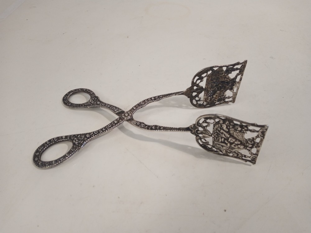 A pair of antique German silver scissor-style cake tongs featuring pierced relief blades and textured arms. View III