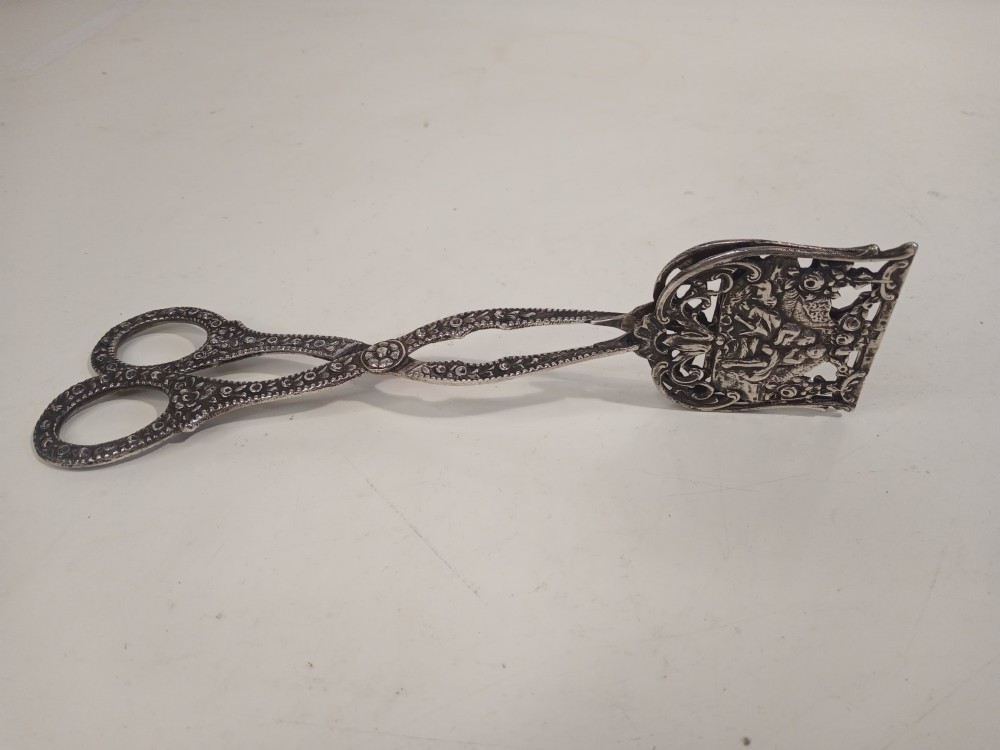 A pair of antique German silver scissor-style cake tongs featuring pierced relief blades and textured arms. View IV