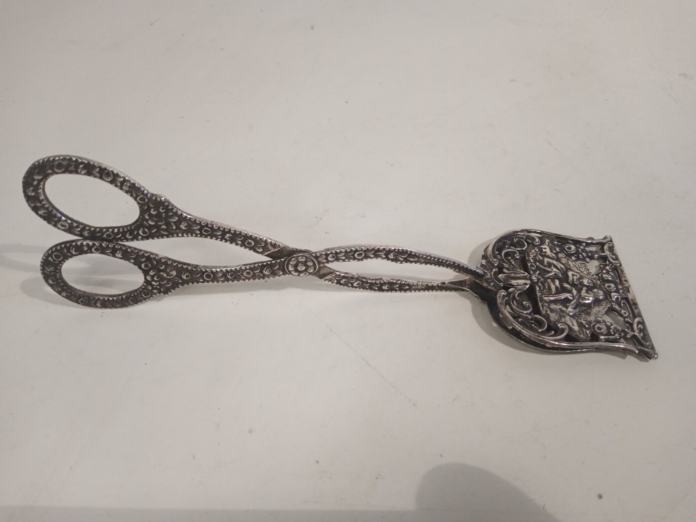 A pair of antique German silver scissor-style cake tongs featuring pierced relief blades and textured arms. View V