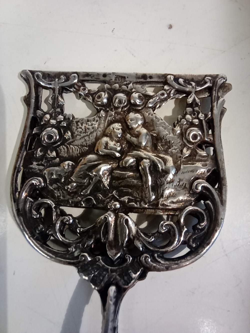 A pair of antique German silver scissor-style cake tongs featuring pierced relief blades and textured arms. View VI