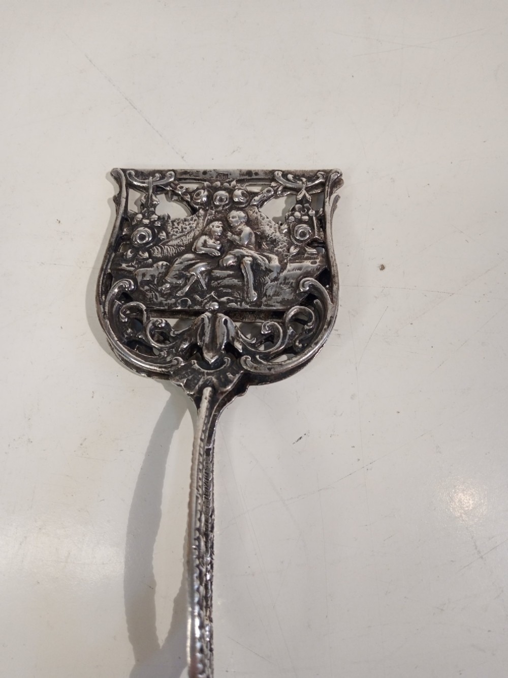A pair of antique German silver scissor-style cake tongs featuring pierced relief blades and textured arms. View VII
