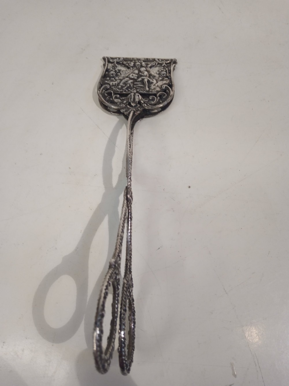 A pair of antique German silver scissor-style cake tongs featuring pierced relief blades and textured arms. View VIII