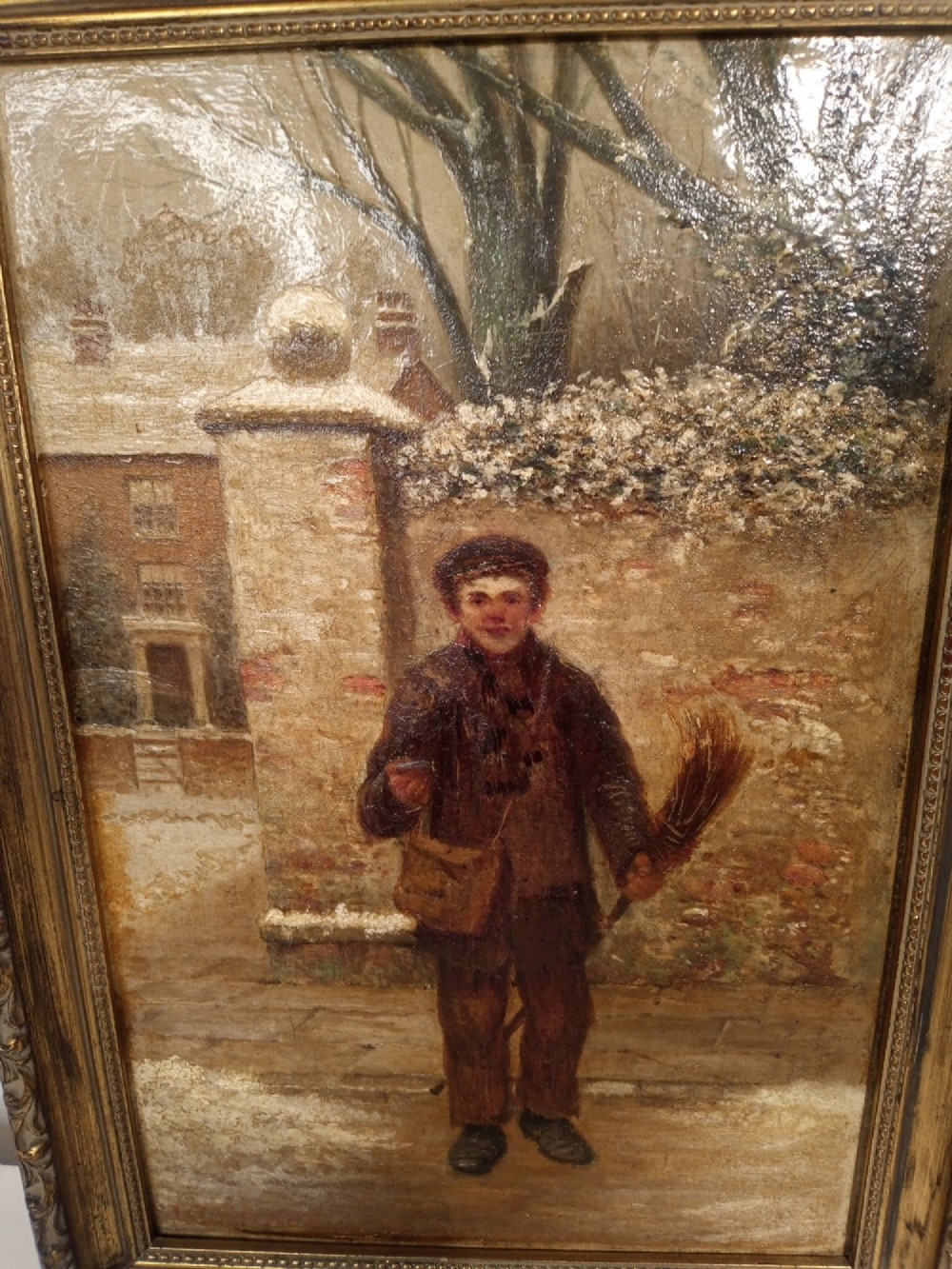 A framed 19th-century oil painting depicting a young chimney sweeper holding a broom in a snowy street scene, set within a gilded moulded frame. View II