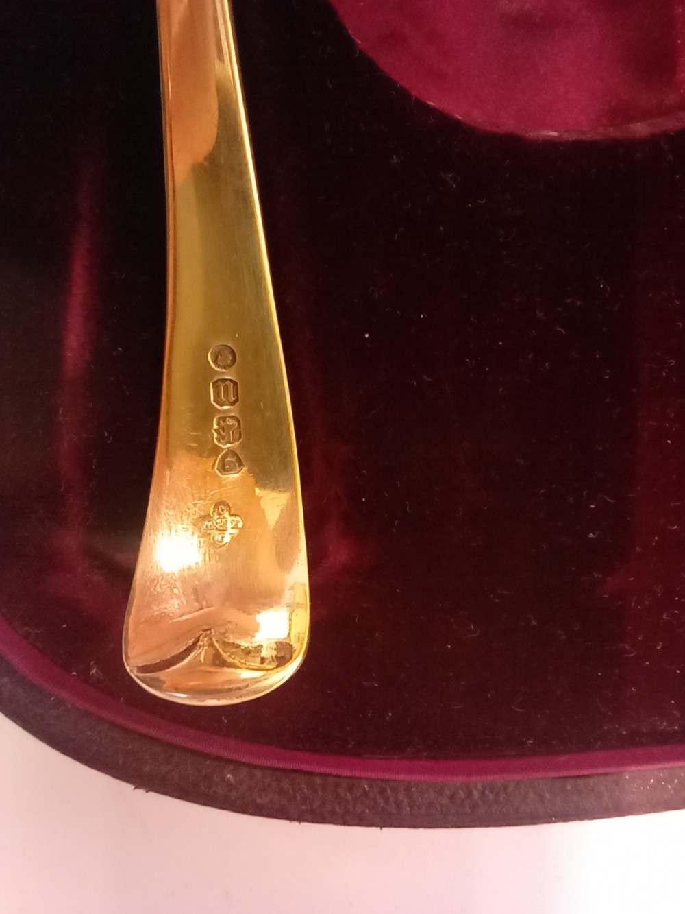 A dark presentation case lined with purple silk containing two embossed silver-gilt berry spoons and a pierced sugar sifter spoon. View IV