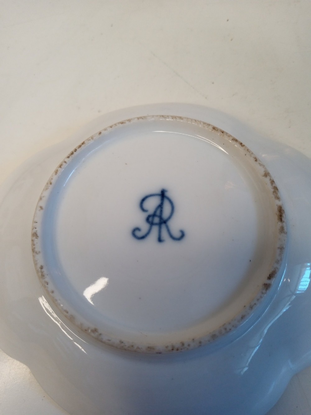 A white porcelain teacup and scalloped saucer decorated with hand-painted multicoloured floral sprays and gold gilded rims. View IV