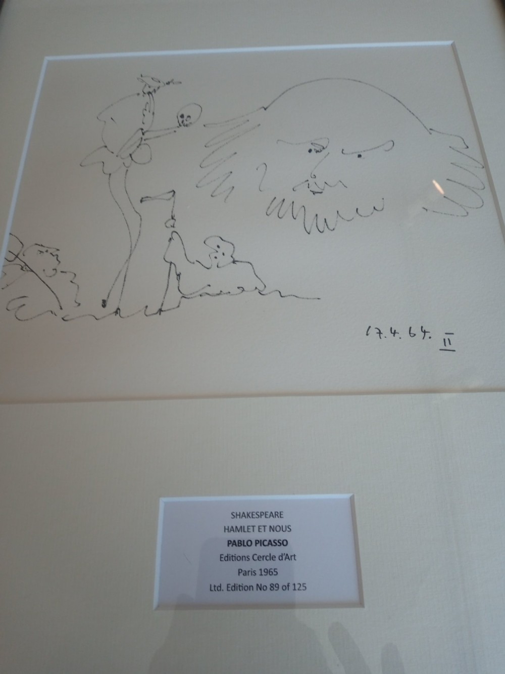 A framed black line drawing print by Pablo Picasso featuring minimalist figures on off-white paper within a black wooden frame. View II