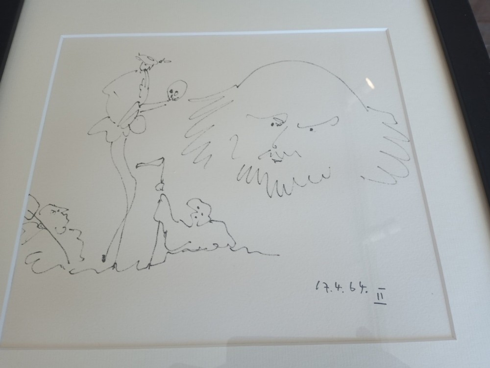 A framed black line drawing print by Pablo Picasso featuring minimalist figures on off-white paper within a black wooden frame. View III