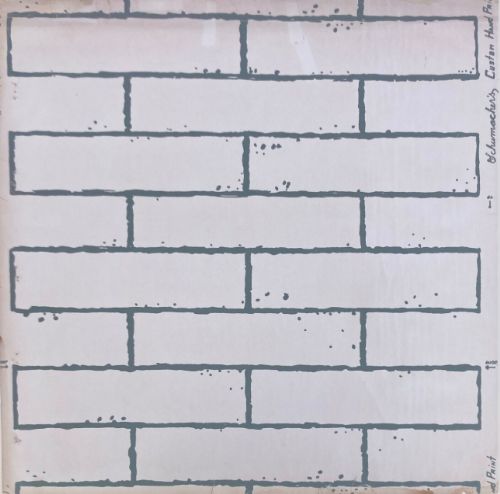 fig 1. A square vintage wallpaper sample featuring a grey hand-printed faux brick wall motif on an off-white background with printed text along the side margins.
