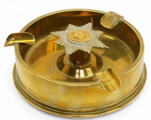 fig 2. Circular brass trench art ashtray formed from a shell casing with three cigarette rests and a central star-shaped military emblem.