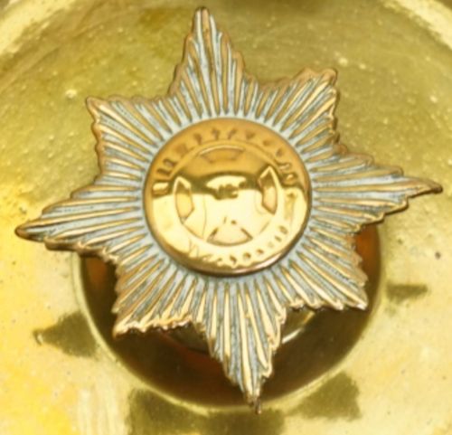 fig 3. Circular brass trench art ashtray formed from a shell casing with three cigarette rests and a central star-shaped military emblem.