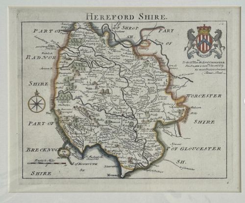 fig 1. An 18th-century hand-coloured copperplate engraved map of Herefordshire detailing county borders, a compass rose, and a heraldic coat of arms.