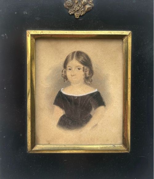 fig 2. An early nineteenth-century watercolour portrait miniature of a young girl with brown hair, presented in a square ebonised frame with a gilt inner slip and top brass hanger.