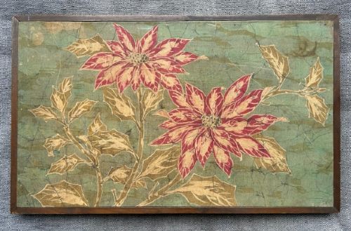 fig 2. A horizontal framed batik textile artwork displaying red and cream poinsettia flowers with foliage against a crackled sage green background.