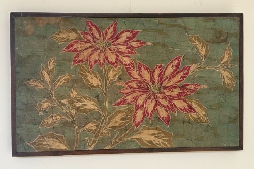 fig 5. A horizontal framed batik textile artwork displaying red and cream poinsettia flowers with foliage against a crackled sage green background.
