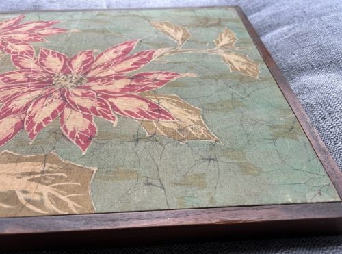 fig 6. A horizontal framed batik textile artwork displaying red and cream poinsettia flowers with foliage against a crackled sage green background.