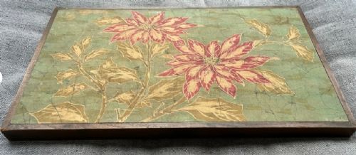 A horizontal framed batik textile artwork displaying red and cream poinsettia flowers with foliage against a crackled sage green background. View VIII