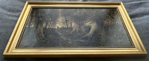 A late nineteenth-century horizontal oil painting depicting a solitary figure walking along a sunlit woodland path framed by large ancient trees within a gold leaf frame. View XII