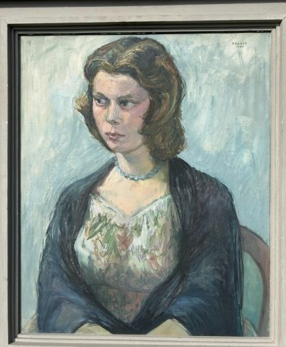fig 2. A mid-century oil painting on canvas depicting a seated woman wearing a patterned dress, blue necklace, and dark shawl, framed in a grey wooden frame.