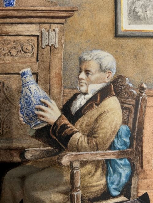 A late 19th-century watercolour painting depicting an elderly gentleman seated in a carved oak chair, examining a blue and white porcelain vase inside a wood-panelled room. View V