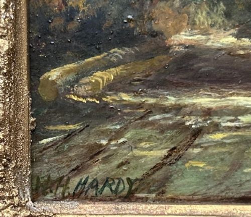 An antique oil painting on panel depicting a rural British cottage surrounded by trees, set within an ornate gilt frame. View VII
