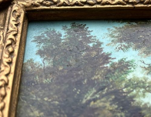 An antique oil painting on panel depicting a rural British cottage surrounded by trees, set within an ornate gilt frame. View IX