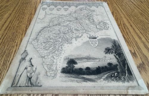 fig 1. A nineteenth-century monochrome steel engraving map of Cumberland by Thomas Moule featuring decorative Gothic tracery borders, coats of arms, and an architectural vignette of Carlisle.