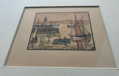 An early 20th-century miniature woodblock print depicting St Ives harbour with a lighthouse, sailing vessels, a rowboat, and coastal hills printed in ink on beige paper. View X