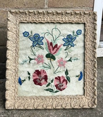 An early 20th-century framed floral embroidery panel featuring colourful hand-stitched blossoms on a cream background set within an ornate relief frame. View II