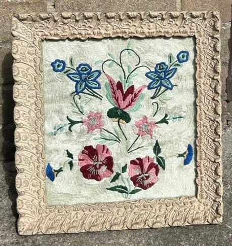 An early 20th-century framed floral embroidery panel featuring colourful hand-stitched blossoms on a cream background set within an ornate relief frame. View IV