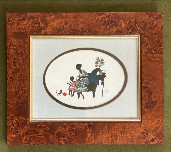 A framed 1920s Art Deco silhouette artwork displaying a mother and child scene inside an oval aperture set within a wide burr walnut frame.