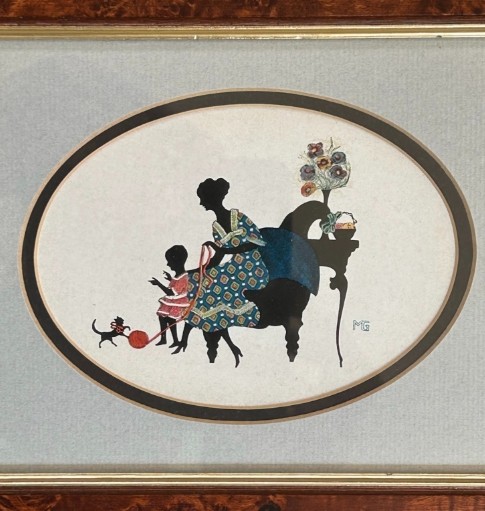A framed 1920s Art Deco silhouette artwork displaying a mother and child scene inside an oval aperture set within a wide burr walnut frame. View III