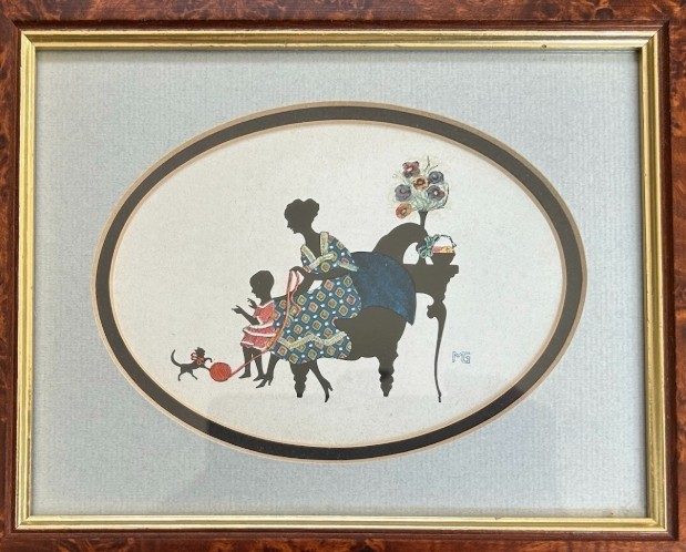 A framed 1920s Art Deco silhouette artwork displaying a mother and child scene inside an oval aperture set within a wide burr walnut frame. View IV