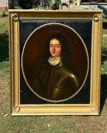 A seventeenth-century oil painting on canvas depicting a gentleman in dark plate armour, set within an oval spandrel inside a decorative giltwood frame. View III