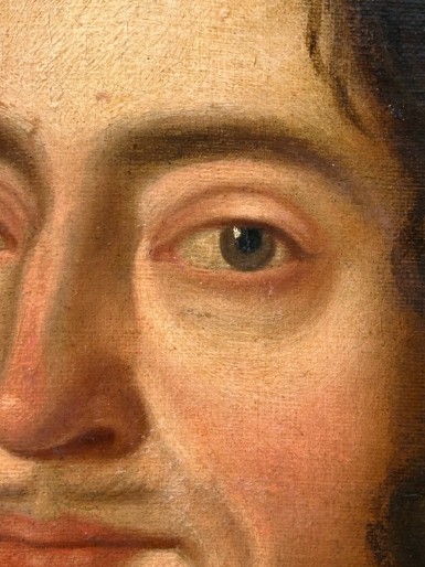 A seventeenth-century oil painting on canvas depicting a gentleman in dark plate armour, set within an oval spandrel inside a decorative giltwood frame. View X