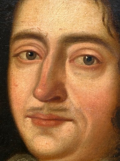 A seventeenth-century oil painting on canvas depicting a gentleman in dark plate armour, set within an oval spandrel inside a decorative giltwood frame. View XI