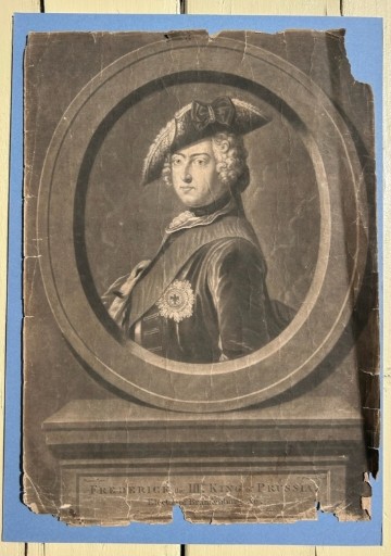 An 18th-century monochrome mezzotint print depicting a bust portrait of Frederick King of Prussia set within a stone oval frame.