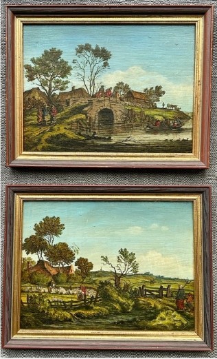 A pair of framed 19th-century oil paintings on wood panels depicting rural Flemish landscapes with stone bridges, rivers, thatched cottages, and pastoral figures.