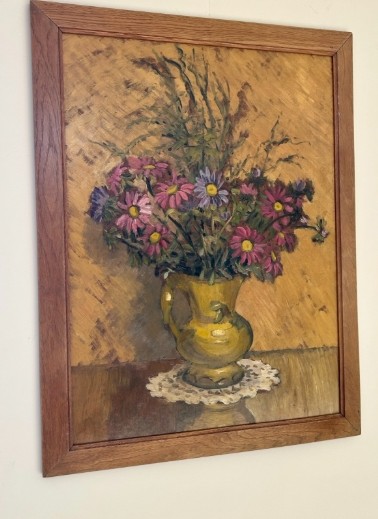A mid-20th century oil painting on board featuring pink and purple flowers in a yellow pitcher against a textured ochre background, presented in a wooden frame. View VI