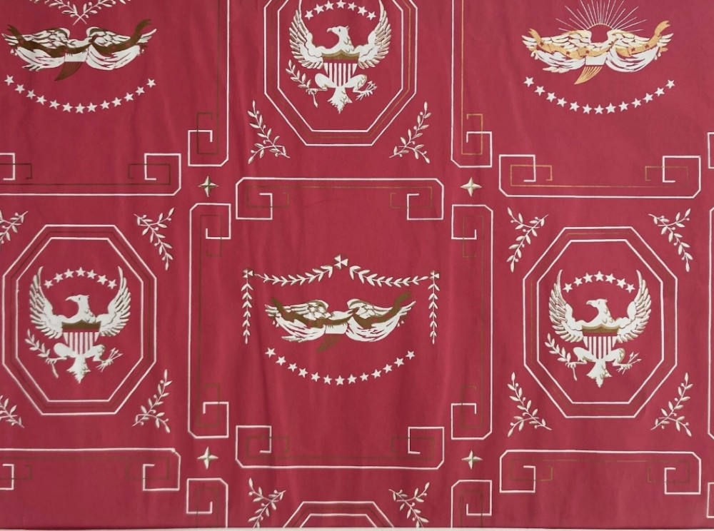 Crimson red hand-printed wallpaper panel featuring white and gold American eagle motifs within octagonal panels, laurel swags, and geometric borders.