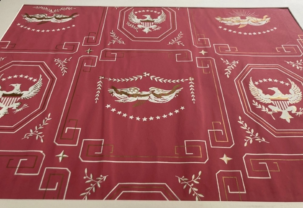 Crimson red hand-printed wallpaper panel featuring white and gold American eagle motifs within octagonal panels, laurel swags, and geometric borders. View VI