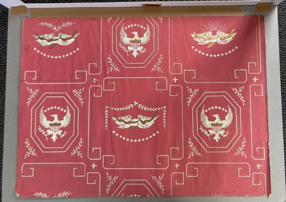 Crimson red hand-printed wallpaper panel featuring white and gold American eagle motifs within octagonal panels, laurel swags, and geometric borders. View VIII