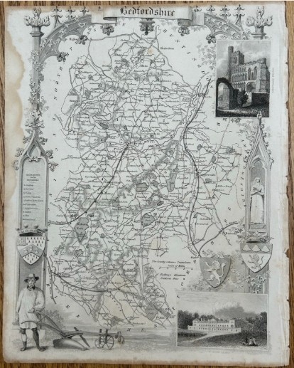 A 19th-century monochrome steel-engraved map of Bedfordshire framed by intricate Gothic architectural arches and regional vignettes including Woburn Abbey.