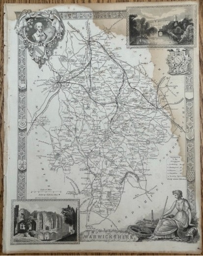 A monochrome 19th-century steel-engraved map of Warwickshire featuring decorative architectural borders, vignette illustrations of Warwick Castle and Kenilworth Castle, and heraldic crests.