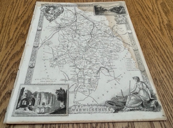 A monochrome 19th-century steel-engraved map of Warwickshire featuring decorative architectural borders, vignette illustrations of Warwick Castle and Kenilworth Castle, and heraldic crests. View II