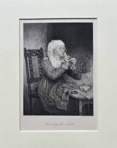 A monochrome nineteenth-century steel engraving depicting an elderly woman wearing spectacles and a headscarf threading a needle while seated at a small wooden table. View II