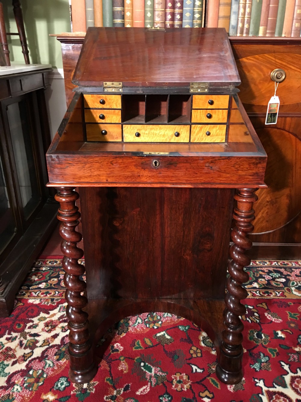 A William IV dark rosewood Davenport writing desk featuring carved barley twist front supports, a sloped writing top, a brass gallery, and side-opening drawers. View IV