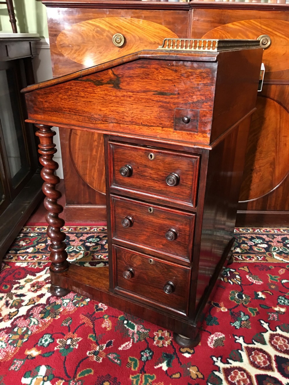 A William IV dark rosewood Davenport writing desk featuring carved barley twist front supports, a sloped writing top, a brass gallery, and side-opening drawers. View VI