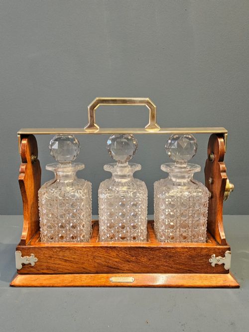 VICTORIAN OAK AND SILVER PLATED THREE BOTTLE TANTALUS