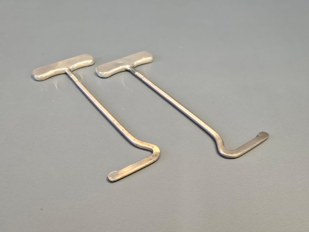 A pair of Edwardian T-bar boot pulls with smooth silver handles and angled metal shafts.