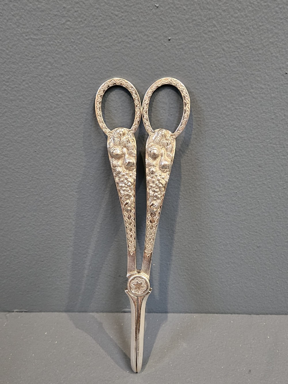 A pair of Victorian cast silver grape scissors with detailed grapevine motifs along the handles.